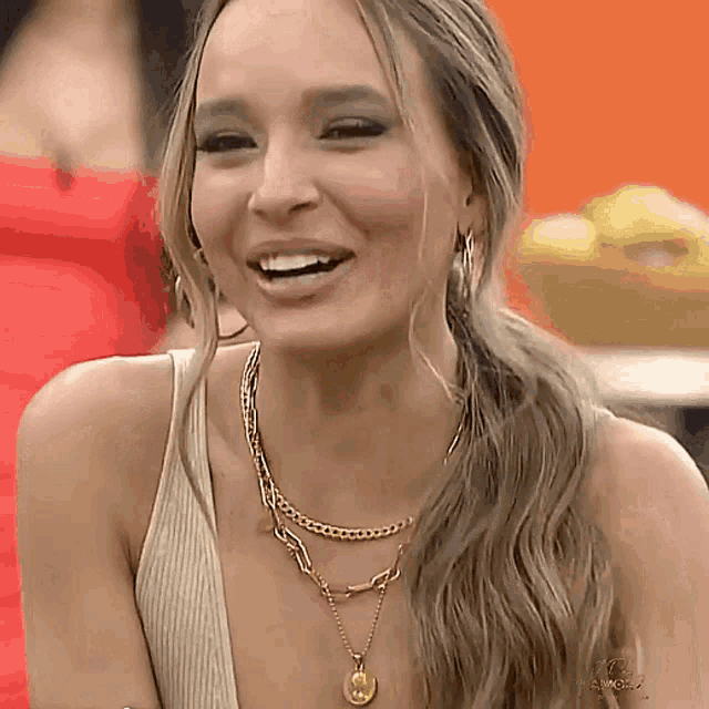 a woman wearing a gold necklace and earrings smiles