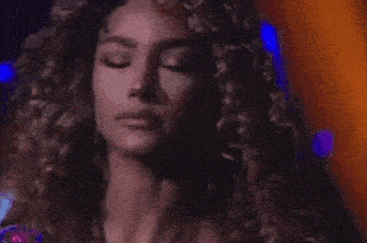 a woman with curly hair is looking down with her eyes closed