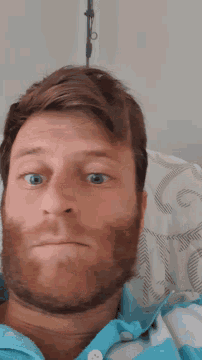 a man with a beard wearing a blue shirt looks at the camera