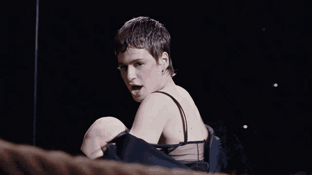 a woman in a black bra is sitting on a rope
