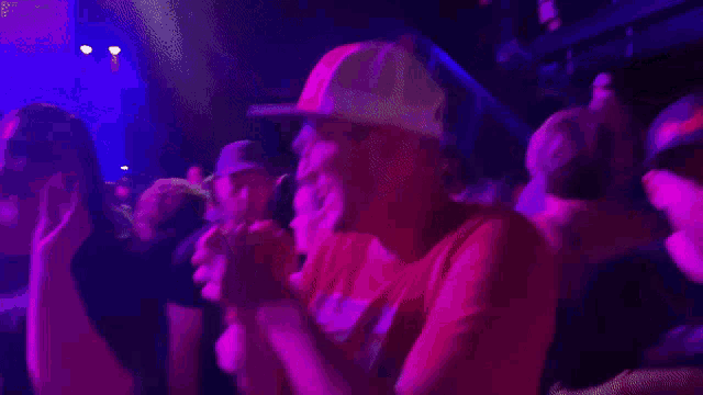 a man in a red shirt is dancing in a crowd at a concert