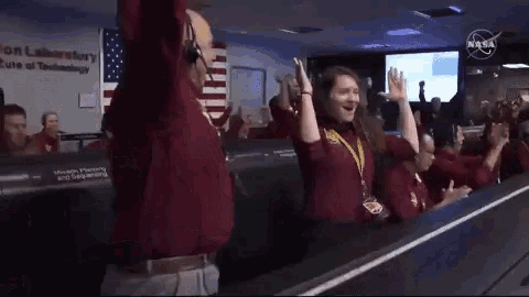 a group of people applaud in front of a nasa sign
