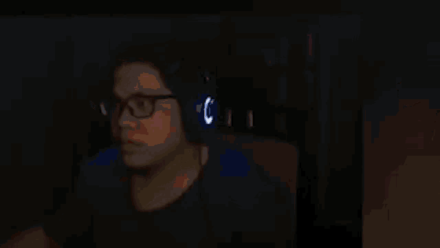 a man wearing headphones is talking on a cell phone in the dark .