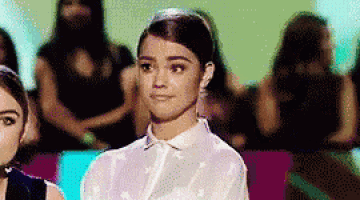 a woman in a white shirt is sitting in front of a crowd .