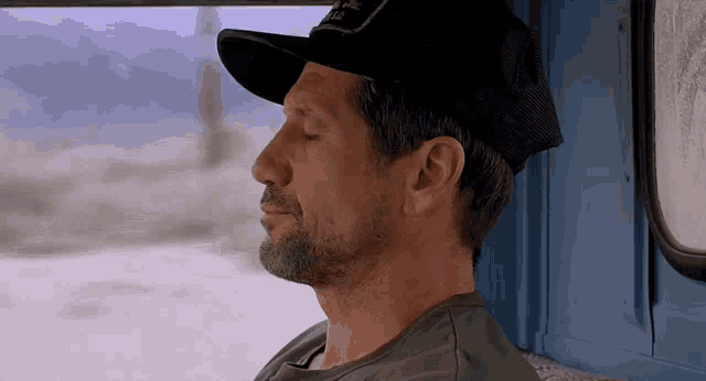 a man with his eyes closed wearing a black hat that says california