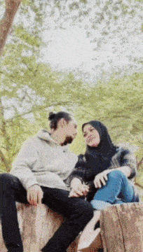 a man and a woman are sitting on a tree stump