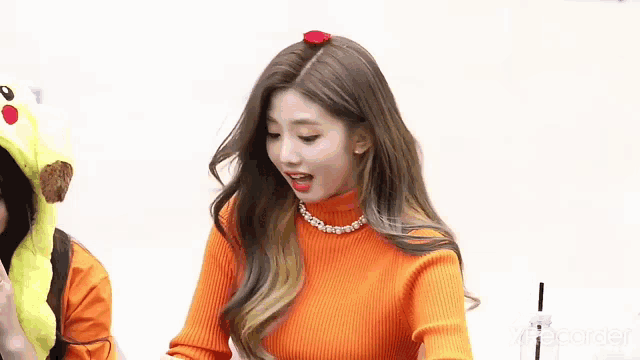 a woman wearing an orange sweater and a flower in her hair