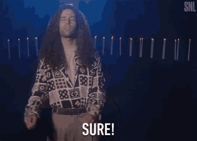 a man with long curly hair is standing in front of candles and says sure