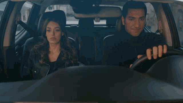 a man is driving a car with a woman sitting in the back