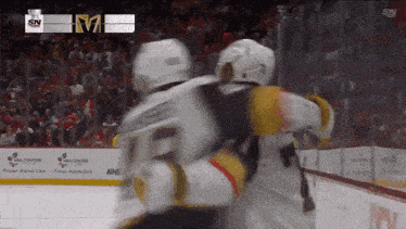two hockey players are hugging each other in front of a banner that says sn