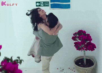 a man is carrying a woman in his arms in front of a sign that says acil cikis