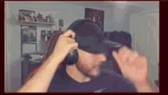 a man wearing headphones and a hat is standing in a room .