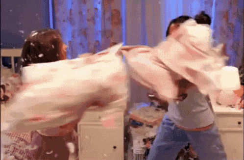 a man and a woman are having a pillow fight .