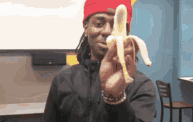 a man in a red hat is holding an opened banana in front of his face