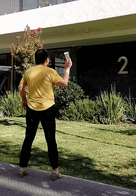 a woman in a yellow shirt is standing in front of a building with the number 2 on it