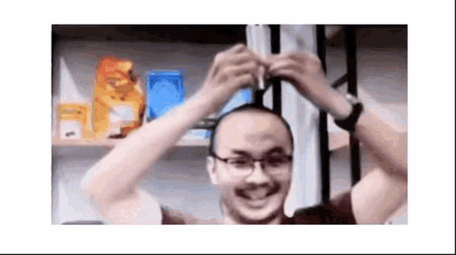 a man wearing glasses is holding his head in his hands and smiling .
