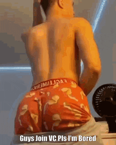 a shirtless man in red underwear is standing in front of a fan and a mirror .