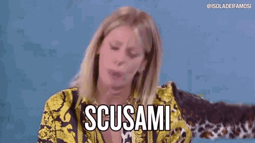 a woman in a yellow and black shirt is making a funny face and saying scusami .