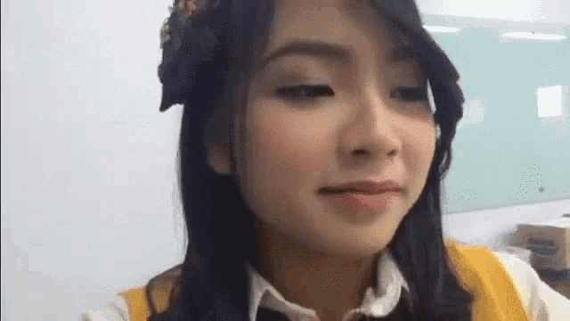 a close up of a woman 's face with a yellow sweater and a headband .