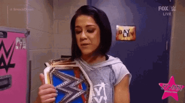 a woman is holding a wrestling championship belt in a room .