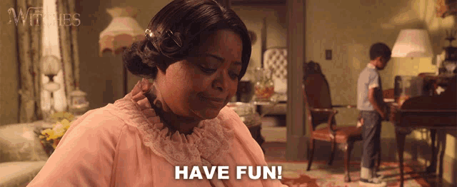 a woman in a pink dress says have fun in a living room