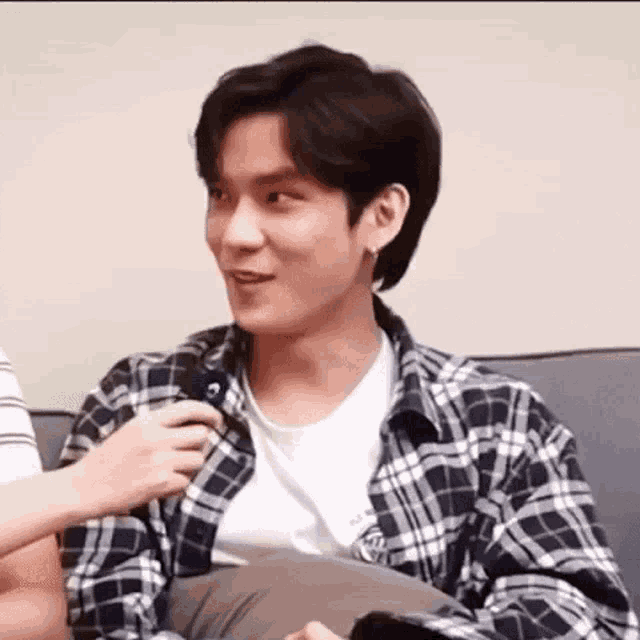 a man in a plaid shirt is sitting on a couch with a person .