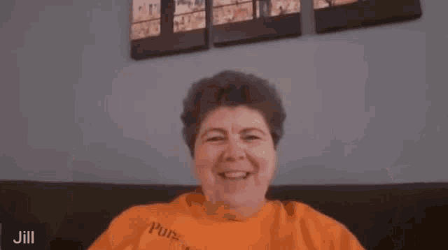 a woman in an orange shirt is making a funny face and says oops