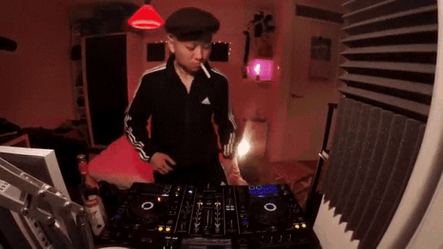 a man is smoking a cigarette while standing in front of a dj mixer .