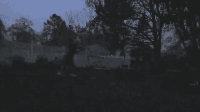 a dark backyard with a fence and trees in the background