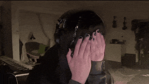a woman wearing headphones covers her face with her hands