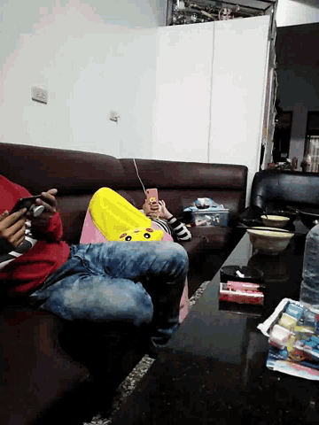 a person laying on a couch with a phone in their hand with the letter m on the front