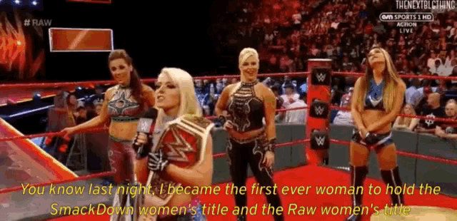 a group of women are standing in a wrestling ring and one of them is holding a smackdown championship