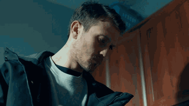 a man in a black jacket looks down in a dark room