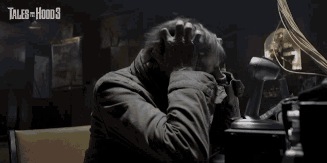 a man sitting at a desk with tales of hood 3 on the bottom right
