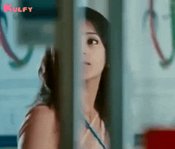 a woman is peeking out of a window and looking at something .