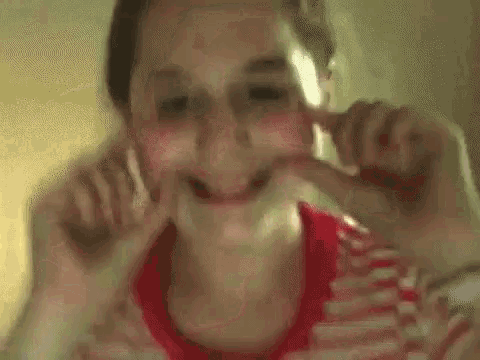 a girl in a red and white striped shirt is making a funny face .