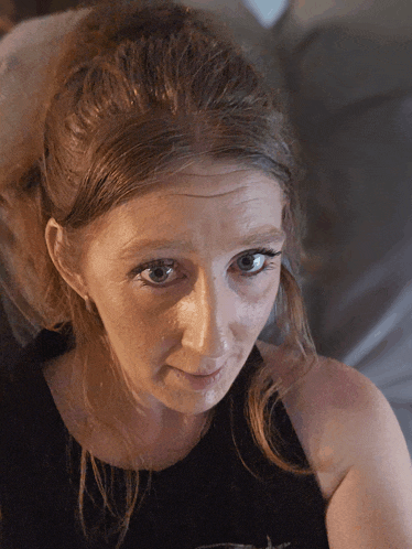 a close up of a woman 's face with a black tank top