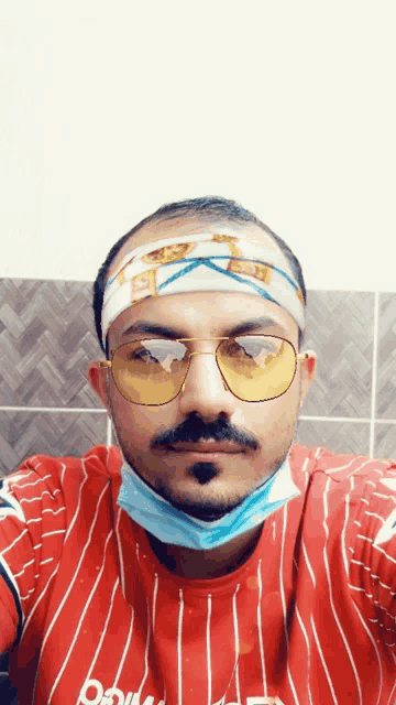 a man wearing sunglasses and a headband with the letter b on it looks at the camera