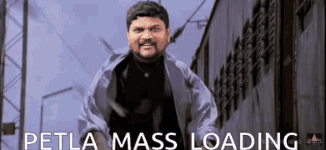 a man with a beard is standing in front of a building with the words petla mass loading behind him