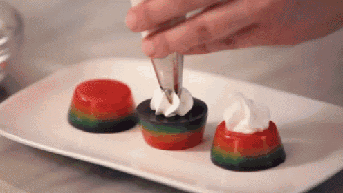 a person is decorating a dessert with whipped cream on top .