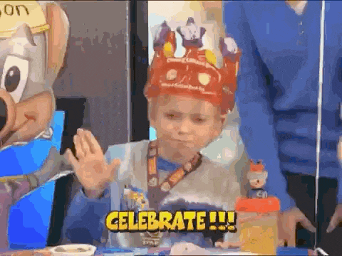 a boy wearing a crown says celebrate while sitting at a table