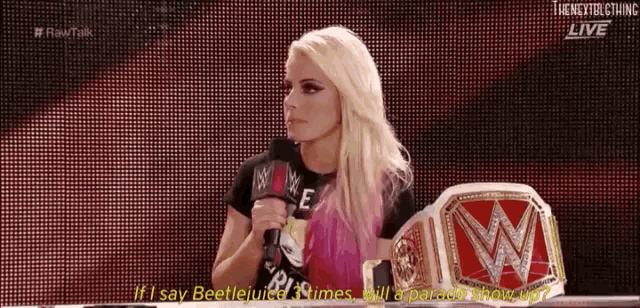a woman is holding a microphone in front of a wrestling ring .