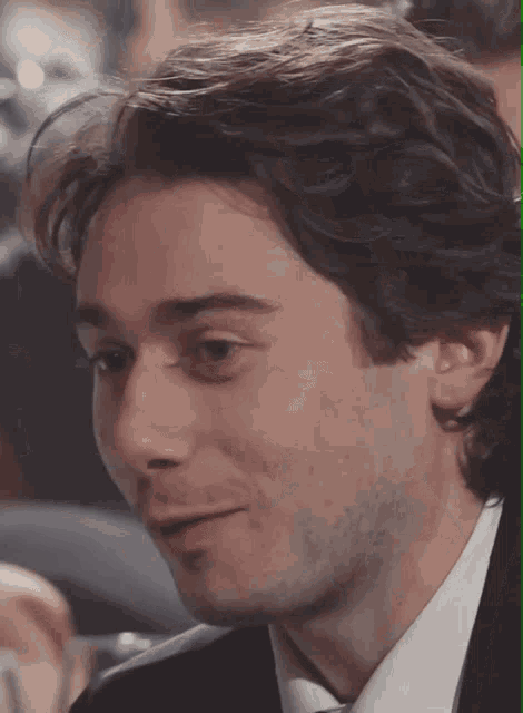 a close up of a man 's face with a suit and tie