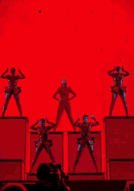 a woman in a red costume is dancing on a stage with other dancers
