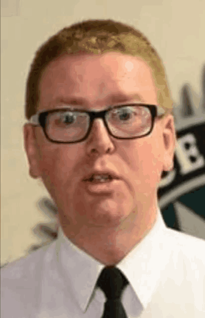 a man wearing glasses and a tie is talking