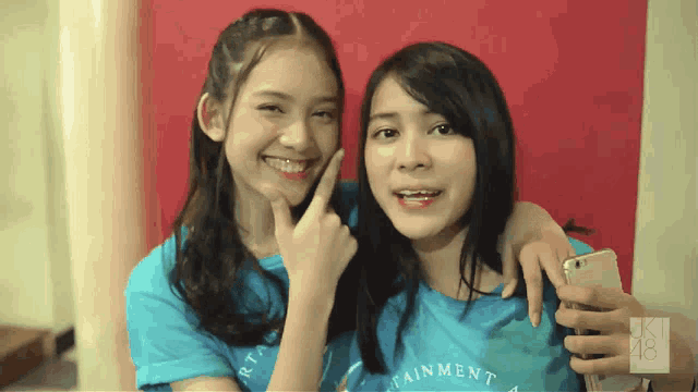 two girls posing for a picture with one wearing a blue shirt that says entertainment