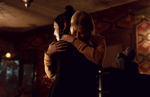 two women hugging in a dark room with candles