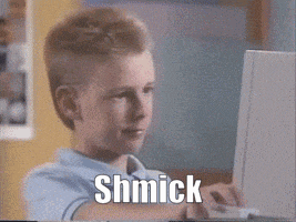 a young boy is typing on a laptop and the word shmick is visible on the screen