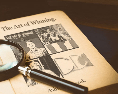 a magnifying glass is sitting on top of a newspaper that says the art of winning