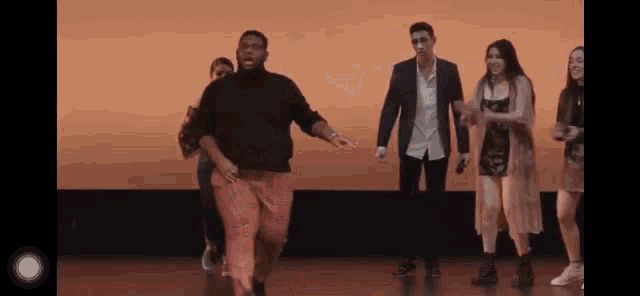 a group of people are dancing on a stage in a room .